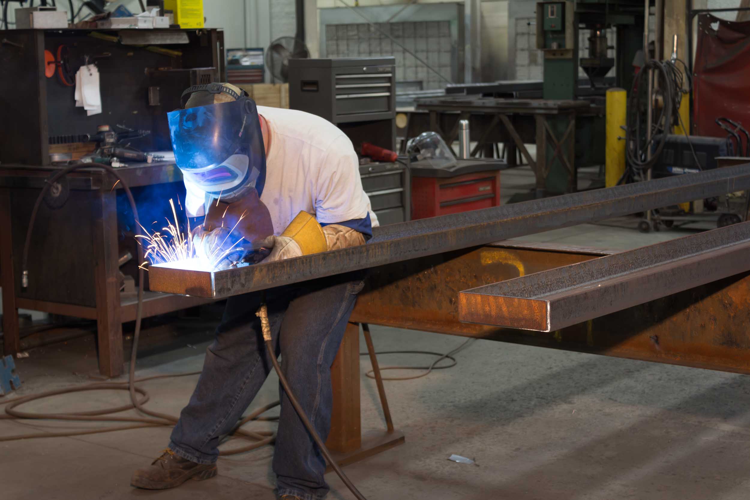 Welder working on metal beam in workshop