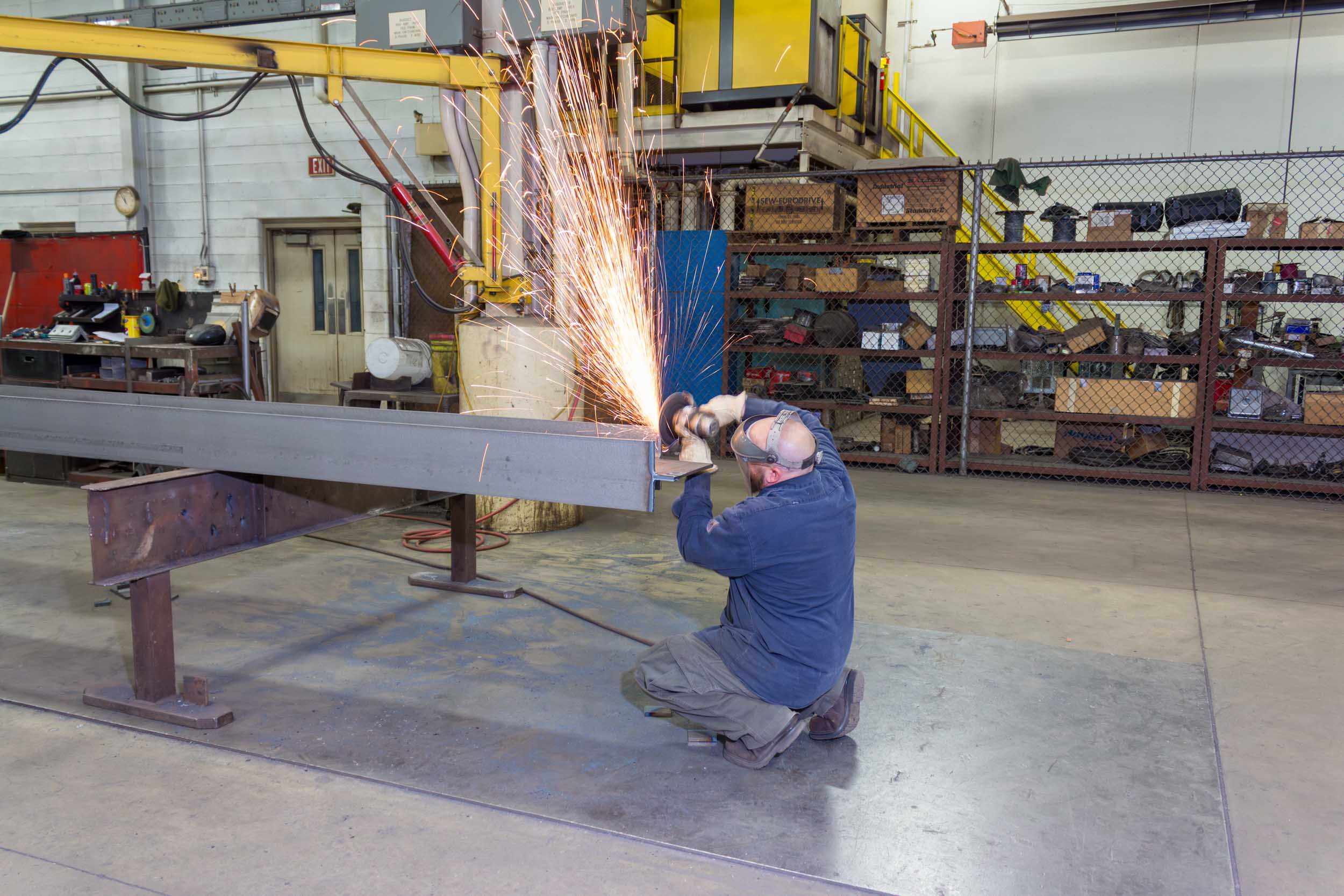 Worker grinding metal beam creating sparks