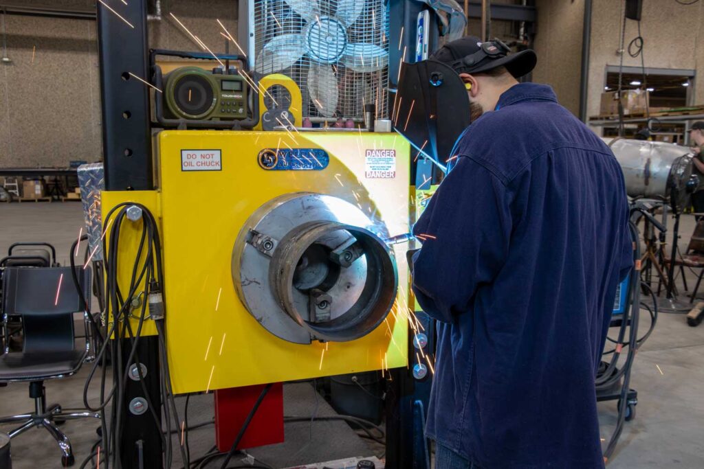 Worker welding metal parts in industrial workshop
