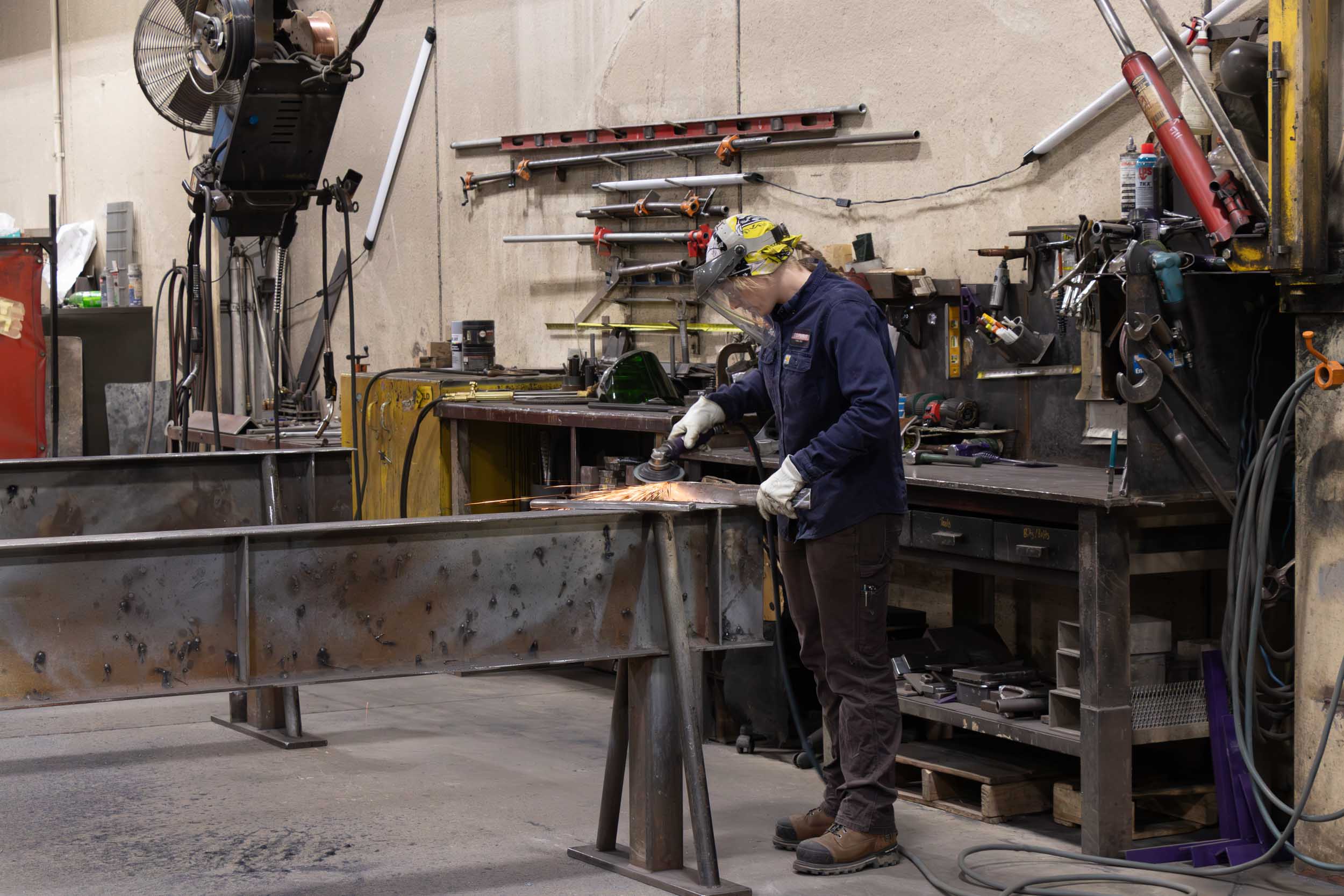 Worker grinding metal beam in industrial workshop