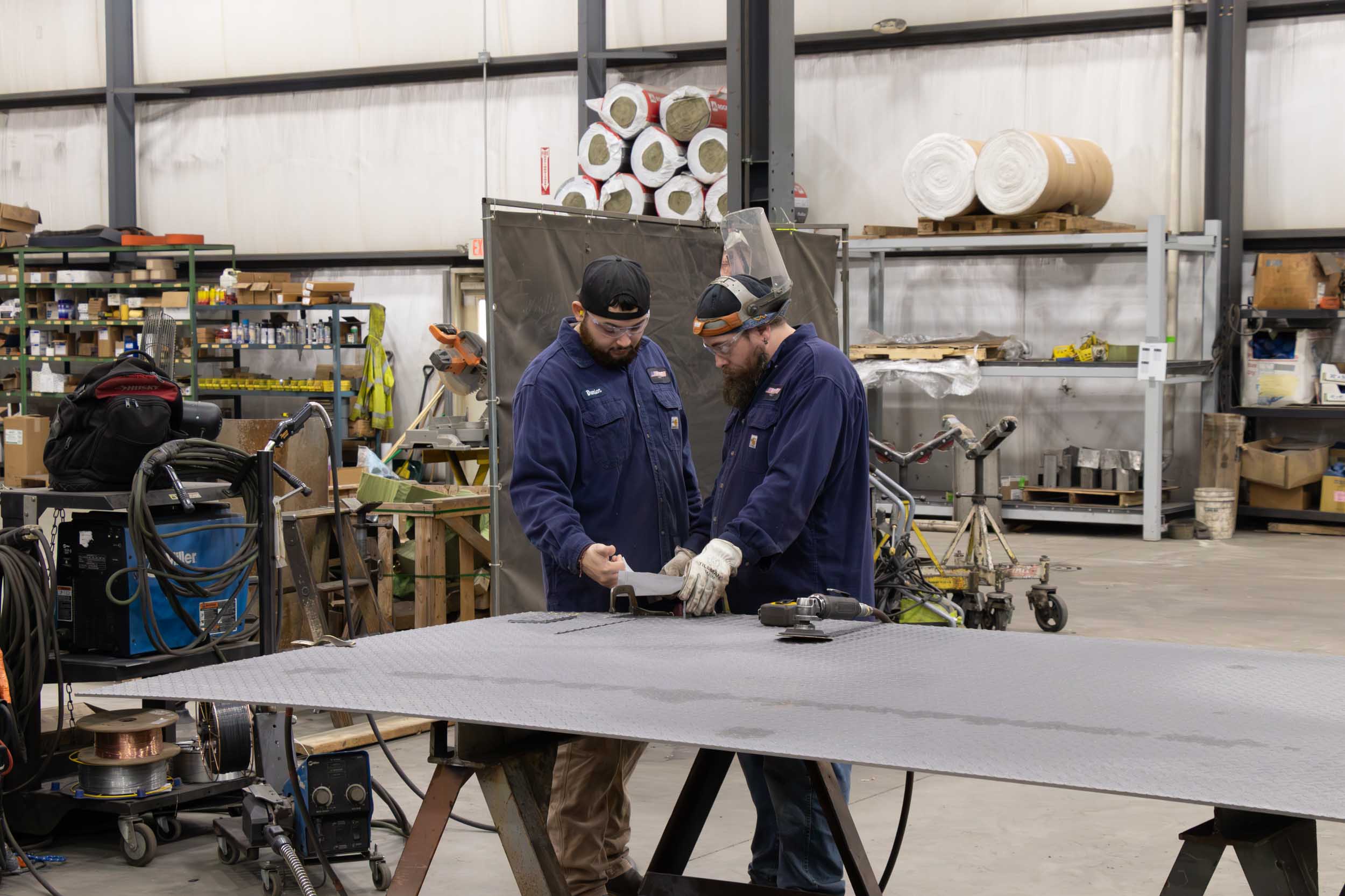 Workers inspecting metal sheet in manufacturing workshop
